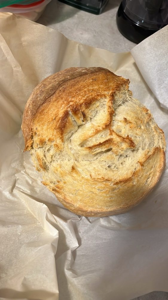 A freshly baked loaf of sourdough bread on parchment paper.